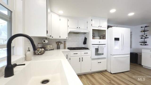 7985 S Cloverdale Rd, Boise, ID 83709 - kitchen featuring under cabinet range hood, light countertops, white appliances, decorative backsplash, and light wood-style flooring