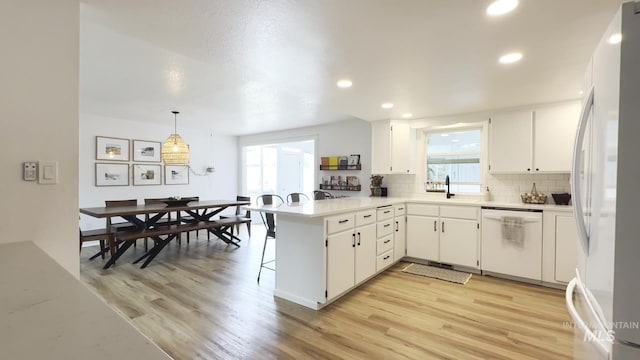 7985 S Cloverdale Rd, Boise, ID 83709 - kitchen featuring a peninsula, tasteful backsplash, light wood-style floors, white appliances, and light countertops