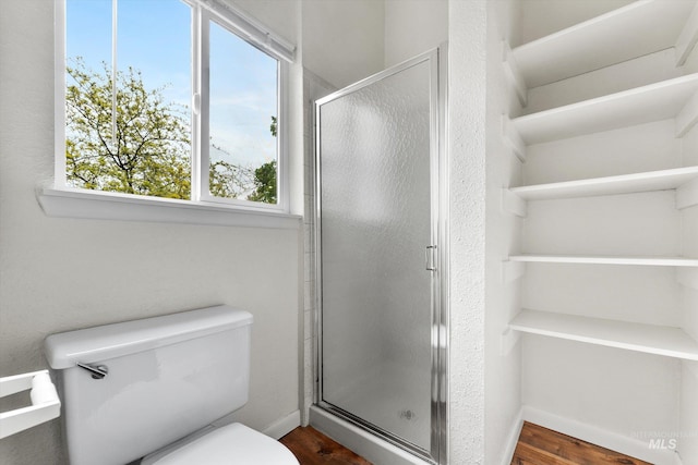 bathroom featuring baseboards, a stall shower, toilet, and wood finished floors