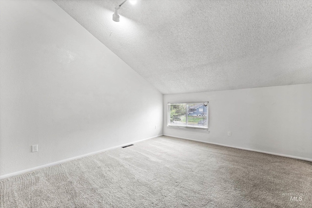carpeted spare room with visible vents, a textured ceiling, baseboards, and track lighting