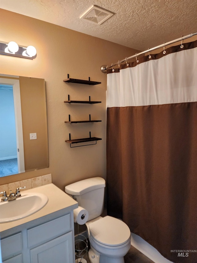 bathroom featuring vanity, toilet, and a textured ceiling