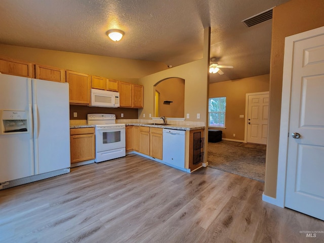 kitchen featuring white appliances, sink, vaulted ceiling, light wood-type flooring, and a textured ceiling