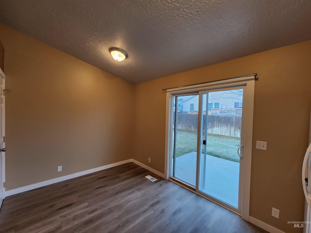 unfurnished room featuring dark hardwood / wood-style flooring and a textured ceiling