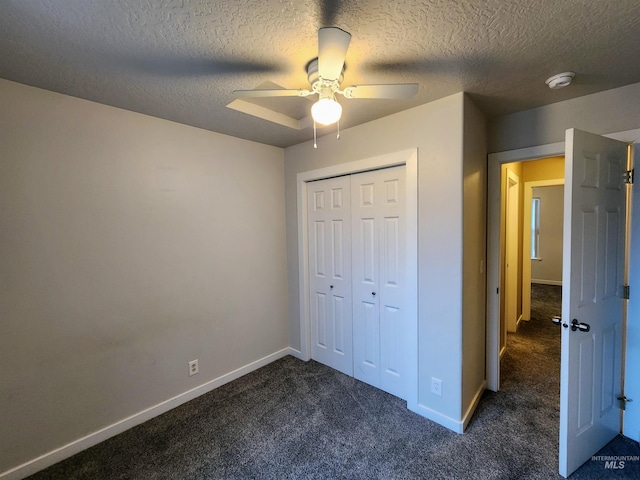 unfurnished bedroom featuring dark colored carpet, ceiling fan, a textured ceiling, and a closet