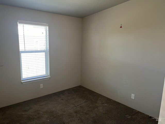 spare room with dark carpet