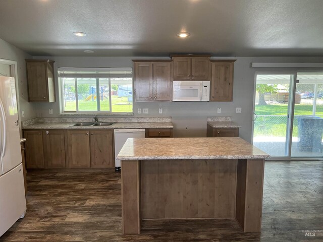 kitchen featuring a sink, white appliances, a textured ceiling, and a wealth of natural light