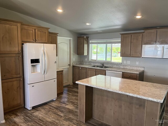 kitchen featuring a sink, white appliances, dark wood finished floors, brown cabinetry, and recessed lighting
