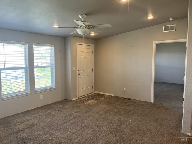 unfurnished room featuring ceiling fan, visible vents, and dark carpet
