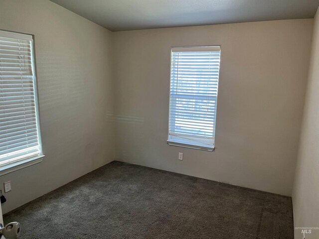 unfurnished room with dark carpet