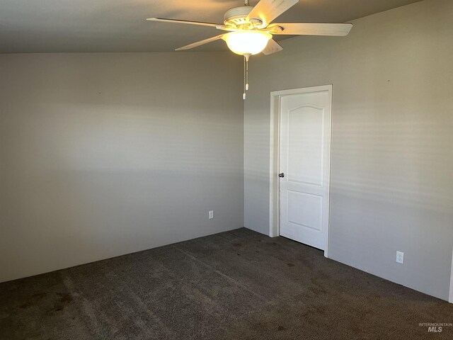 unfurnished room with dark carpet and a ceiling fan