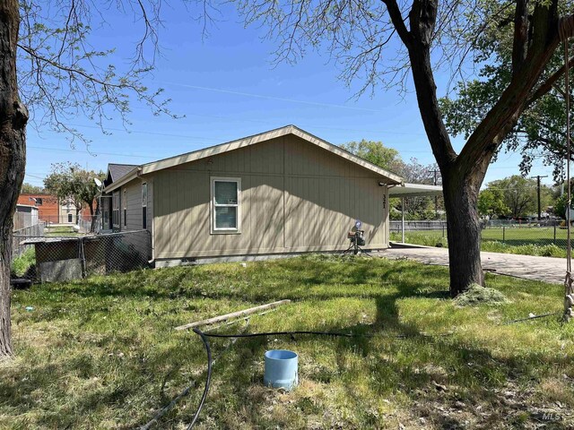 view of home's exterior with a yard, fence, driveway, and a carport