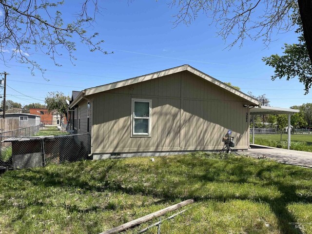 view of property exterior featuring fence, a carport, a yard, and driveway