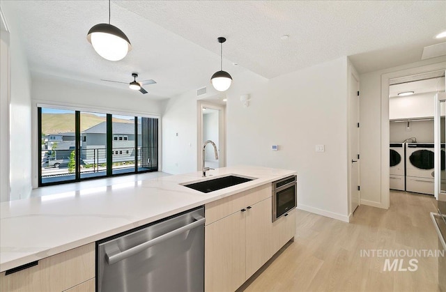 4340 E Haystack St Unit 204, Boise, ID 83716 - kitchen with stainless steel dishwasher, separate washer and dryer, light wood finished floors, pendant lighting, and light stone counters