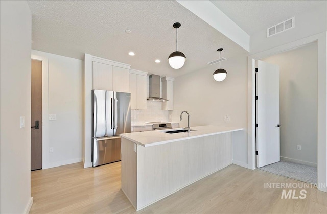 4340 E Haystack St Unit 204, Boise, ID 83716 - kitchen with stainless steel appliances, wall chimney range hood, light wood-type flooring, a peninsula, and light countertops