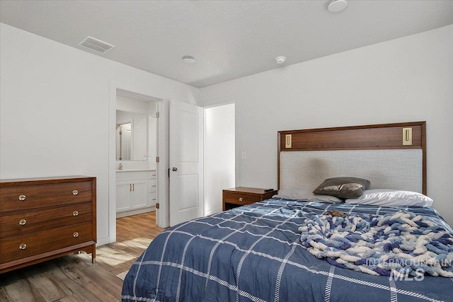 bedroom with wood finished floors and ensuite bath