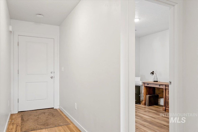 corridor featuring light wood-style flooring and baseboards
