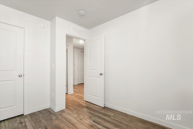 unfurnished bedroom with wood finished floors and baseboards