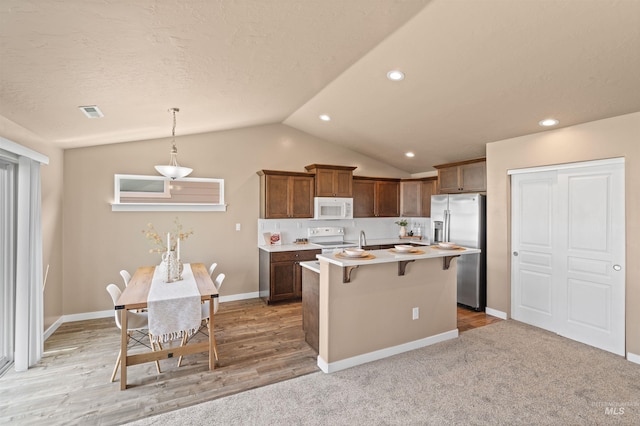 6296 W Mattawa Dr, Meridian, ID 83646 - kitchen featuring light countertops, an island with sink, white appliances, a kitchen bar, and lofted ceiling