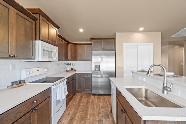 6296 W Mattawa Dr, Meridian, ID 83646 - kitchen featuring recessed lighting, white appliances, decorative backsplash, light wood finished floors, and a sink
