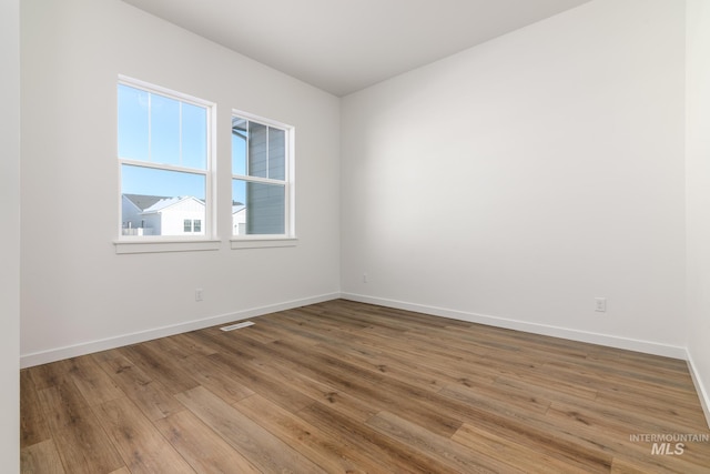 unfurnished room featuring visible vents, baseboards, and wood finished floors