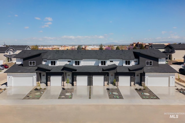 view of property featuring a garage, stone siding, a residential view, and concrete driveway