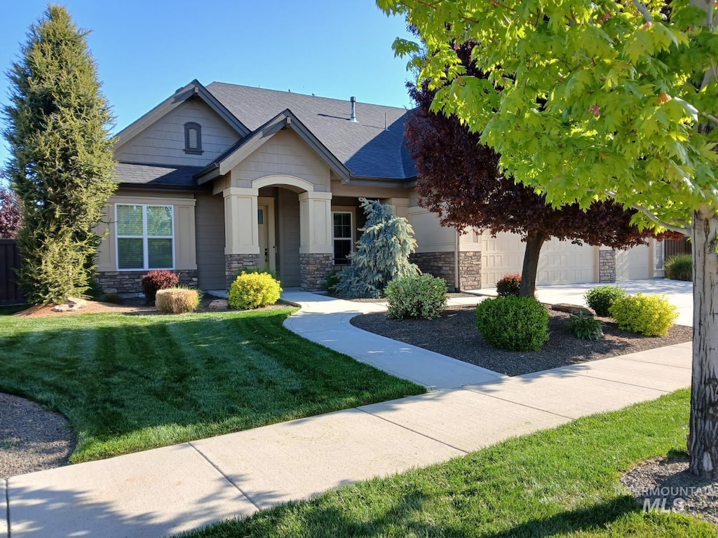 4234 W Wolf Rapids St, Meridian, ID 83646 - craftsman-style house with stone siding, a garage, a front lawn, and roof with shingles