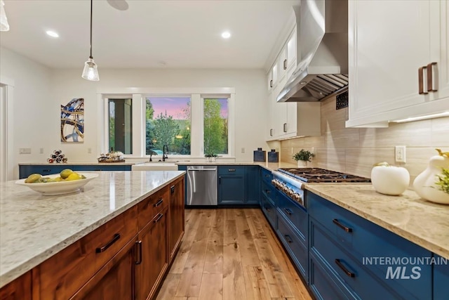 421 E Fishing Creek Ln, Eagle, ID 83616 - kitchen featuring wall chimney range hood, appliances with stainless steel finishes, blue cabinets, light stone counters, and recessed lighting