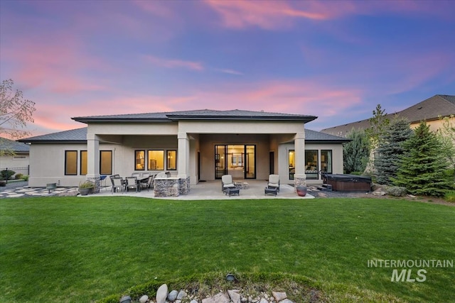 421 E Fishing Creek Ln, Eagle, ID 83616 - back of property at dusk featuring a hot tub, a patio, a yard, and stucco siding