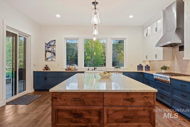 421 E Fishing Creek Ln, Eagle, ID 83616 - kitchen featuring wall chimney range hood, blue cabinetry, stainless steel gas stovetop, white cabinets, and light stone counters