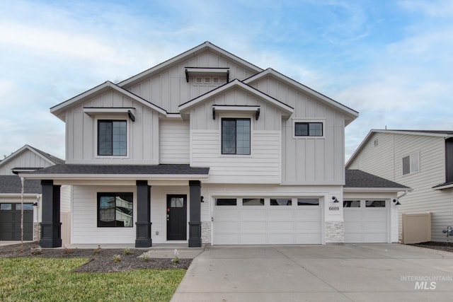 view of front of house featuring a garage, roof with shingles, board and batten siding, and driveway