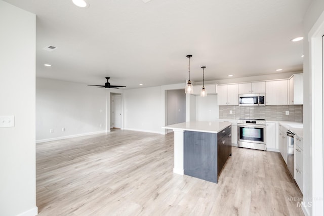 kitchen featuring light wood finished floors, a kitchen island, stainless steel appliances, white cabinets, and tasteful backsplash