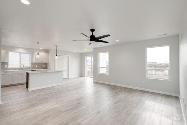 unfurnished living room with a healthy amount of sunlight, light wood finished floors, and a sink