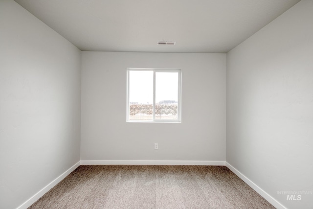 carpeted spare room with visible vents and baseboards