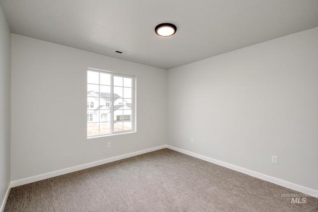 empty room featuring visible vents, carpet floors, and baseboards