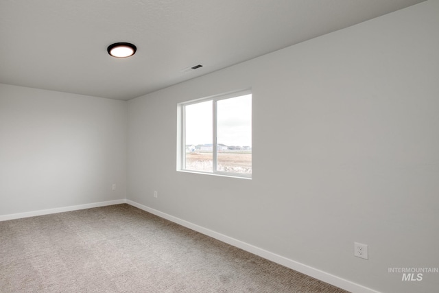 spare room with visible vents, baseboards, and light colored carpet