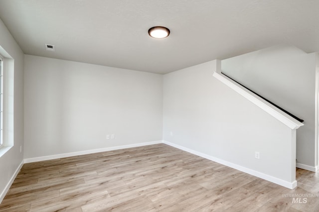 spare room featuring light wood-style flooring, visible vents, and baseboards