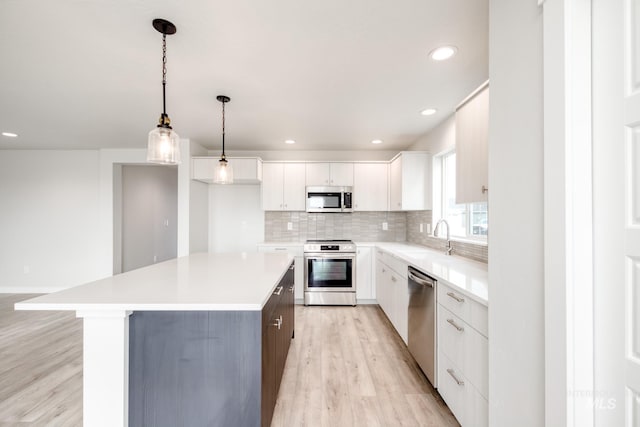 kitchen with a center island, decorative backsplash, appliances with stainless steel finishes, white cabinetry, and a sink