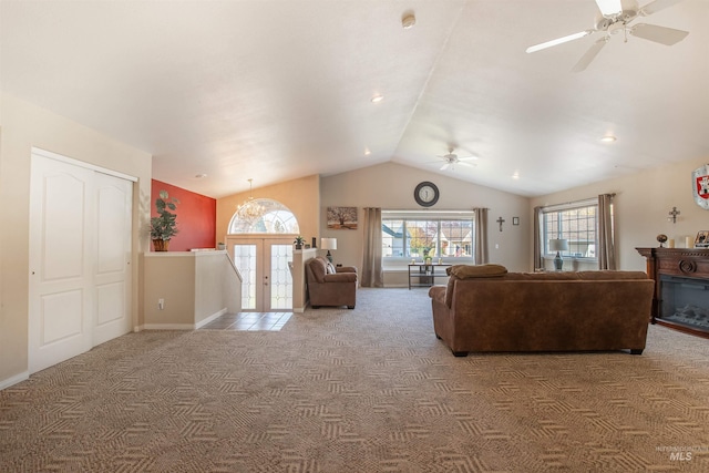 carpeted living room featuring baseboards, a glass covered fireplace, lofted ceiling, ceiling fan, and french doors