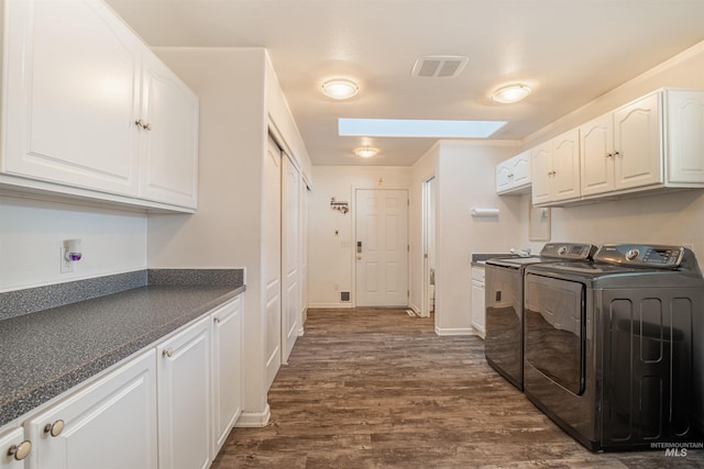 clothes washing area featuring separate washer and dryer, dark wood-type flooring, a skylight, visible vents, and cabinet space