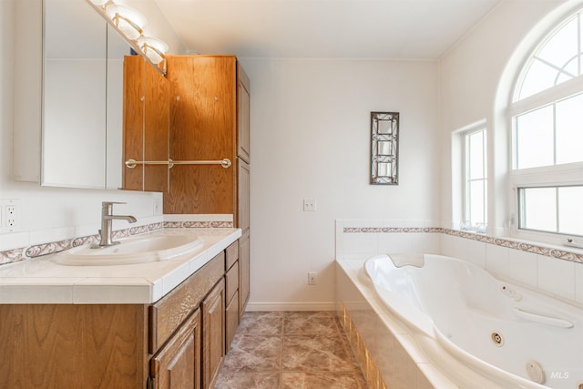 bathroom with a whirlpool tub, tile patterned flooring, baseboards, and vanity