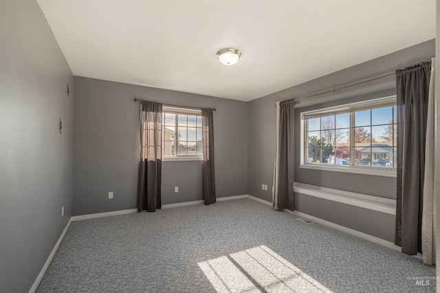 carpeted spare room featuring visible vents and baseboards