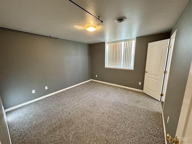 carpeted empty room featuring visible vents, a textured ceiling, and baseboards