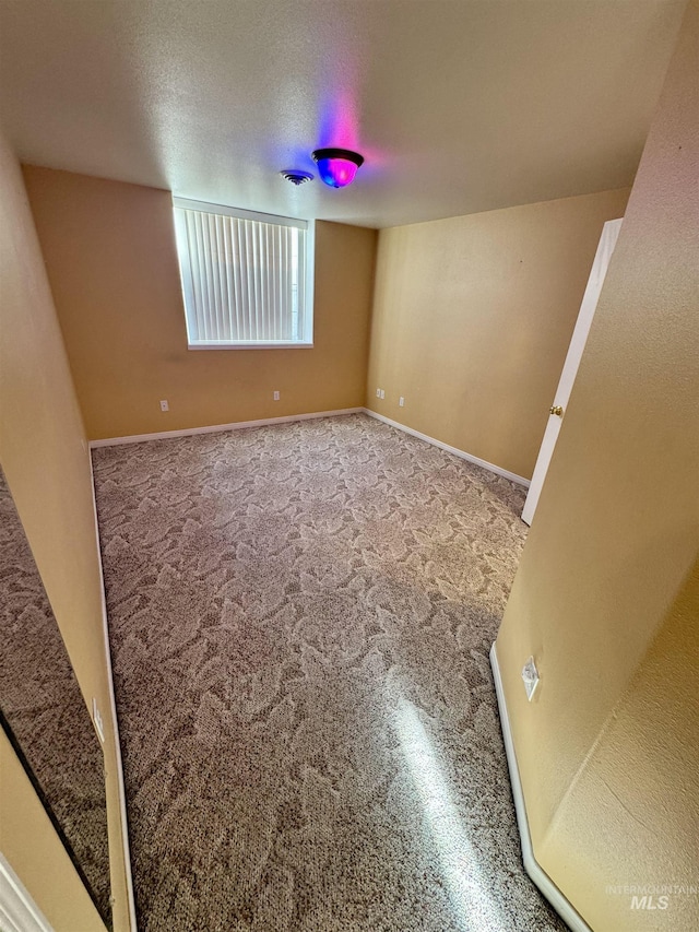 empty room with carpet, visible vents, and baseboards