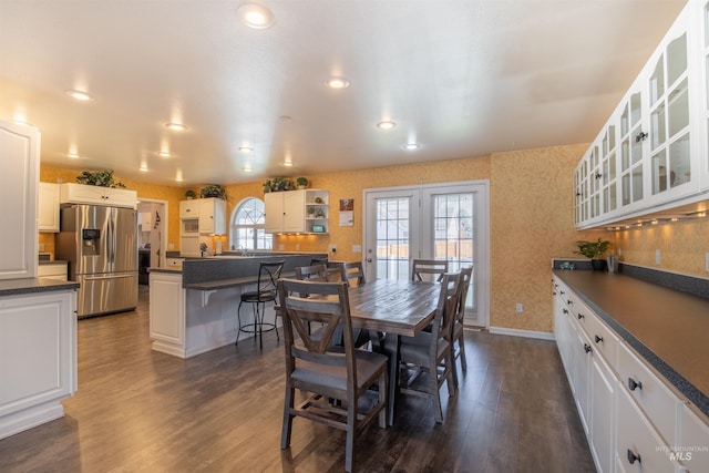 dining area featuring dark wood-style flooring, a healthy amount of sunlight, and wallpapered walls