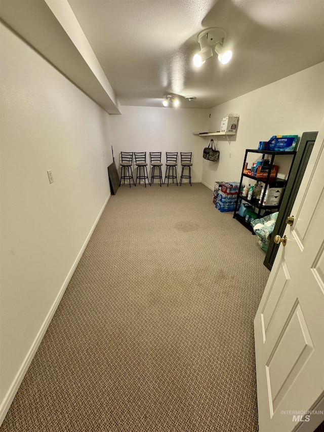 interior space featuring a textured ceiling, baseboards, and carpet flooring