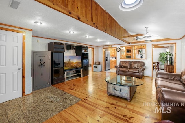 living room with ornamental molding, light hardwood / wood-style floors, ceiling fan, and a textured ceiling