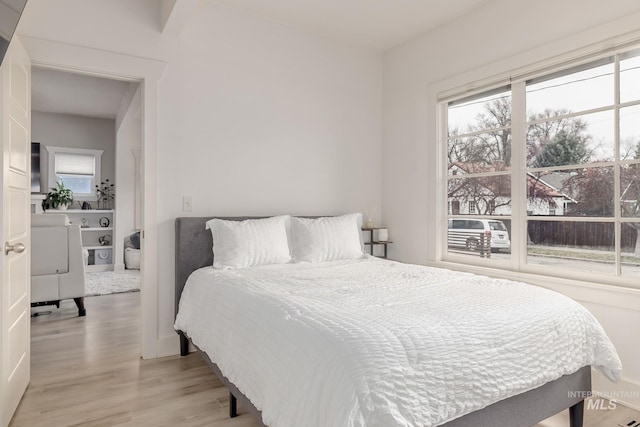 bedroom with multiple windows and light wood finished floors