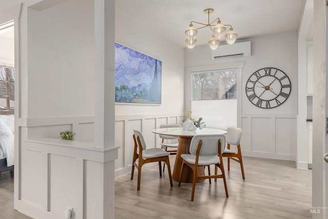 dining area with an inviting chandelier, a decorative wall, light wood-style flooring, and a wall mounted AC