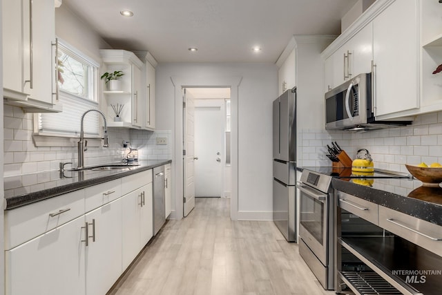 kitchen featuring open shelves, a sink, white cabinets, appliances with stainless steel finishes, and light wood-type flooring