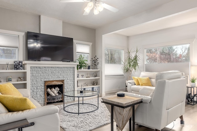 living area with a fireplace, wood finished floors, and a ceiling fan